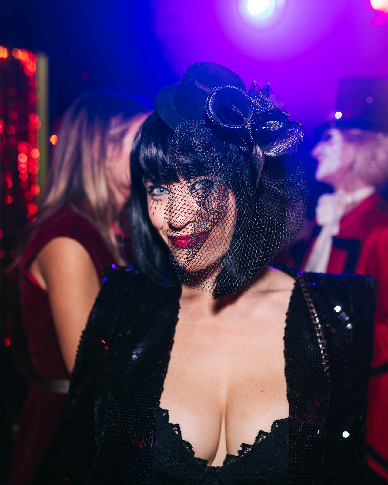 Party photographer London capturing woman in Halloween costume with fascinator and veil in nightclub lighting