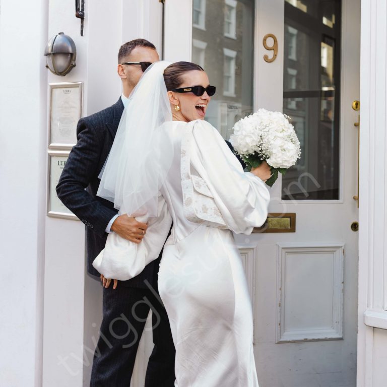 Newlywed couple wearing sunglasses entering a restaurant reception in London after their registry office wedding.