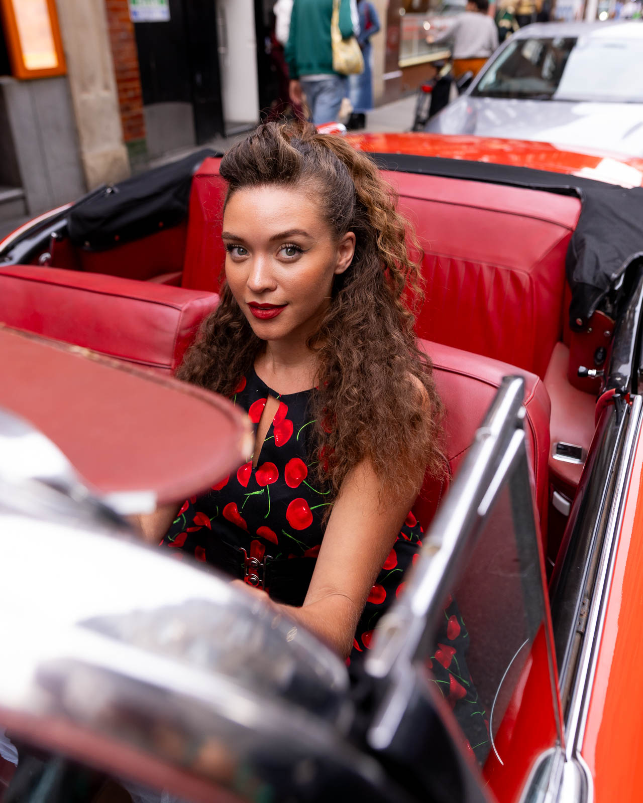 Editorial portrait of woman in red convertible car in London with vibrant styling and natural light