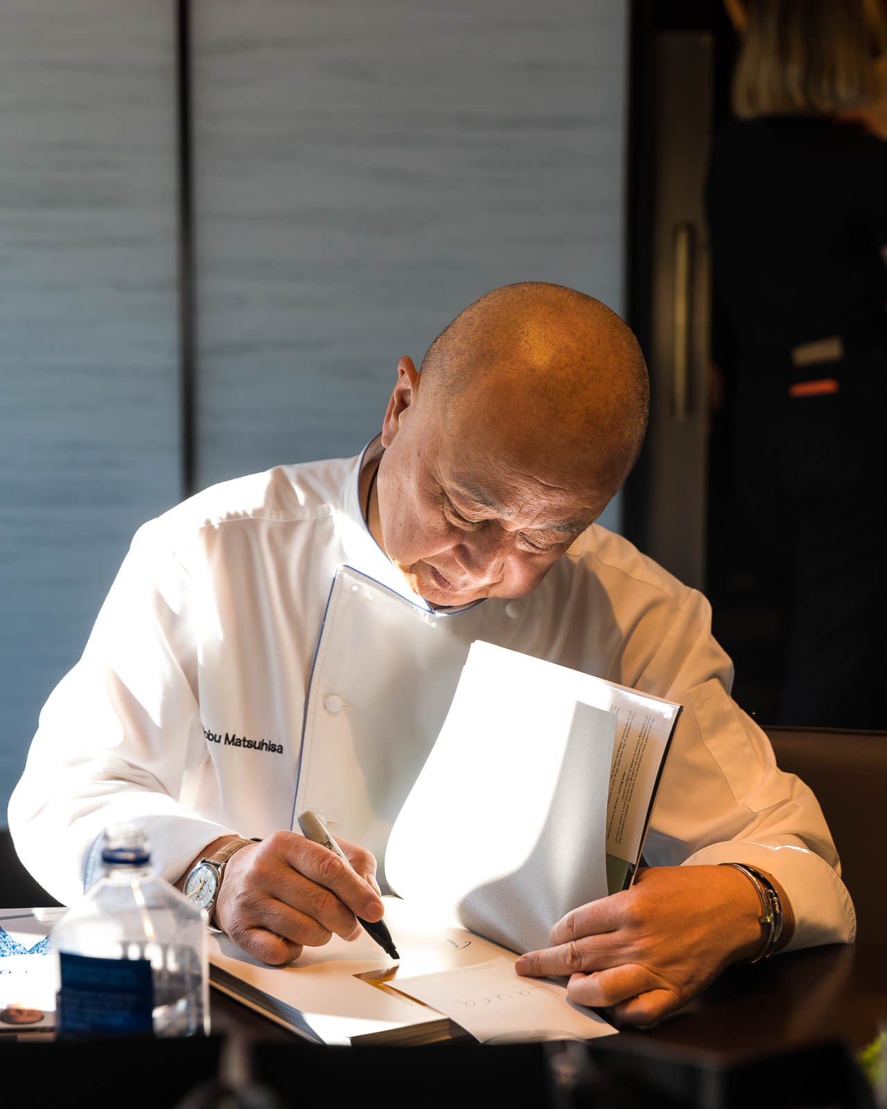 Renowned Chef Nobu at a London event signing a book in a refined, intimate setting
