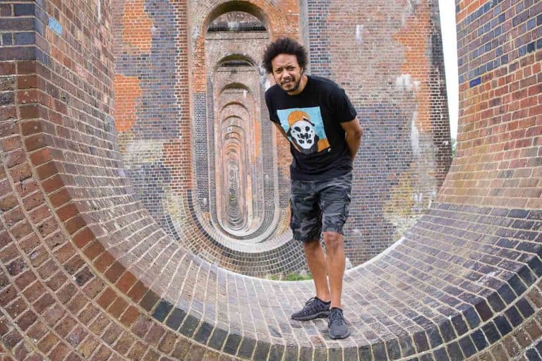 Clothing designer posing in a London brick architectural setting, photographed by Twiggles UK