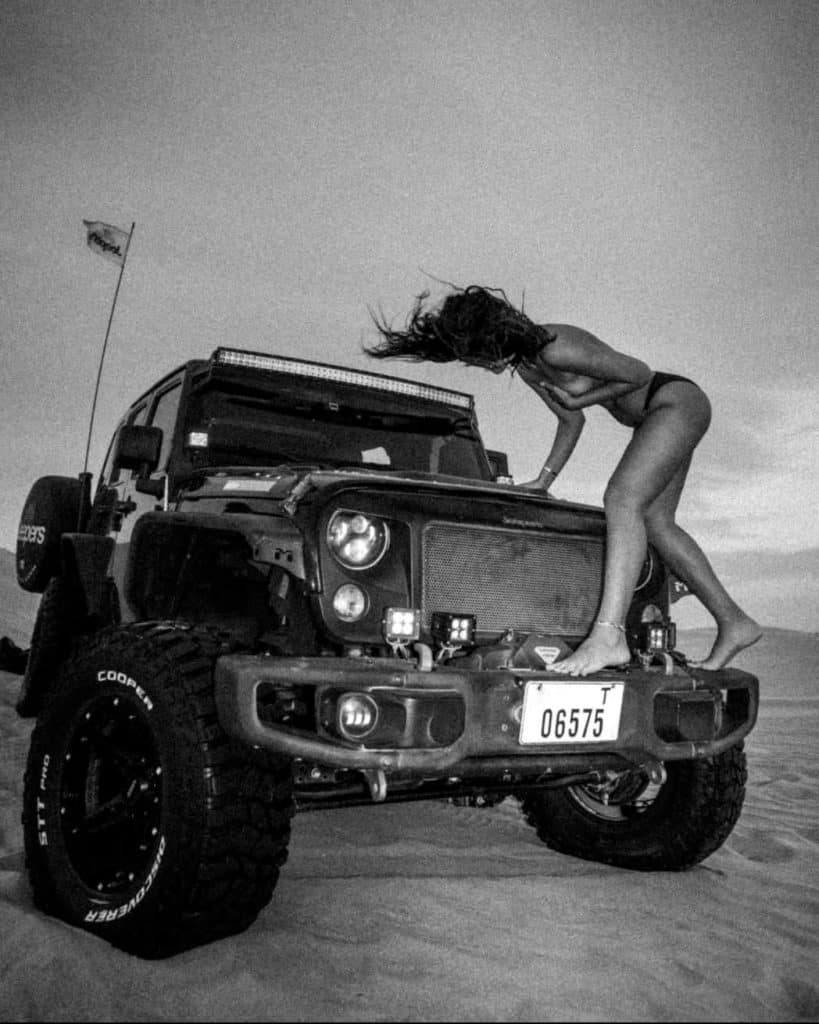 BEEP!, a striking black and white fine art photograph by London artist Twiggles, featuring a woman posed on the bonnet of a rugged off-road vehicle, creating a bold, playful and cinematic composition.