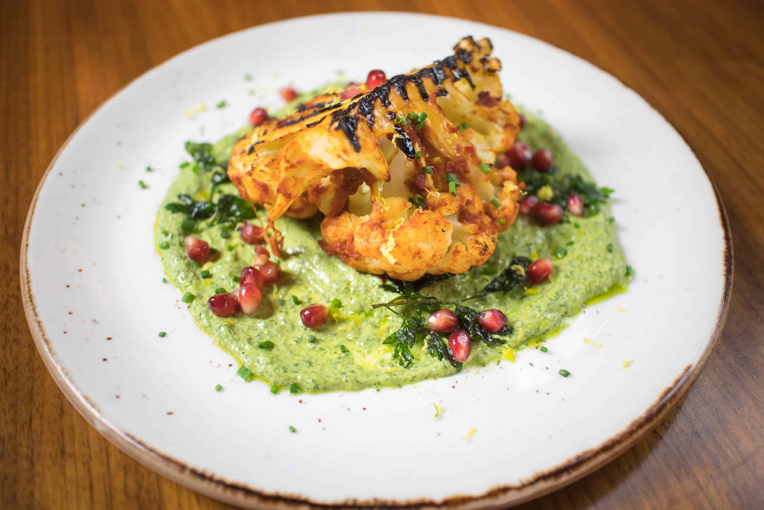 Grilled cauliflower dish with green sauce and pomegranate vegetarian photography
